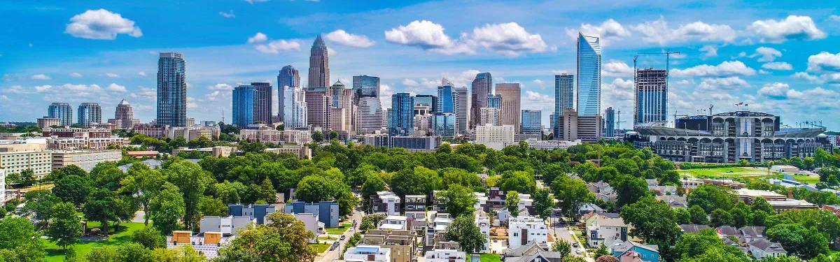 The uptown Charlotte, North Carolina skyline rising beyond a tree-lined neighborhood