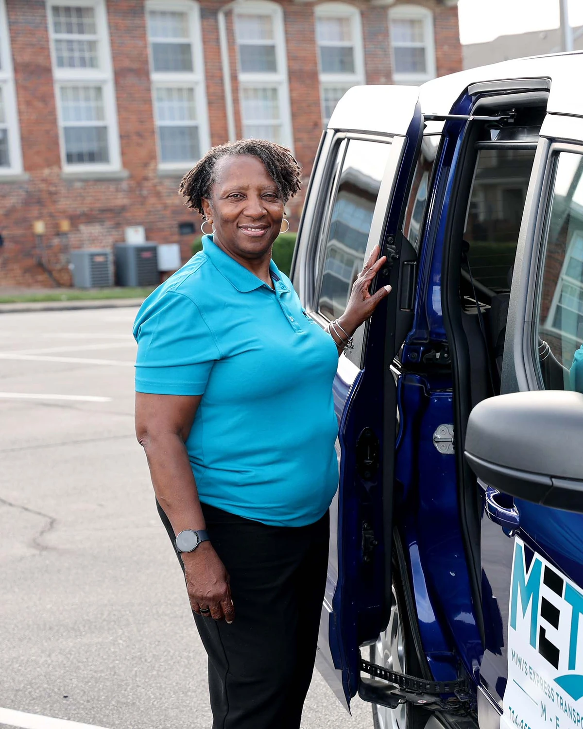 Lisa Bowden, owner and driver of Mimi's Express, smiling beside the open door of her blue METS van
